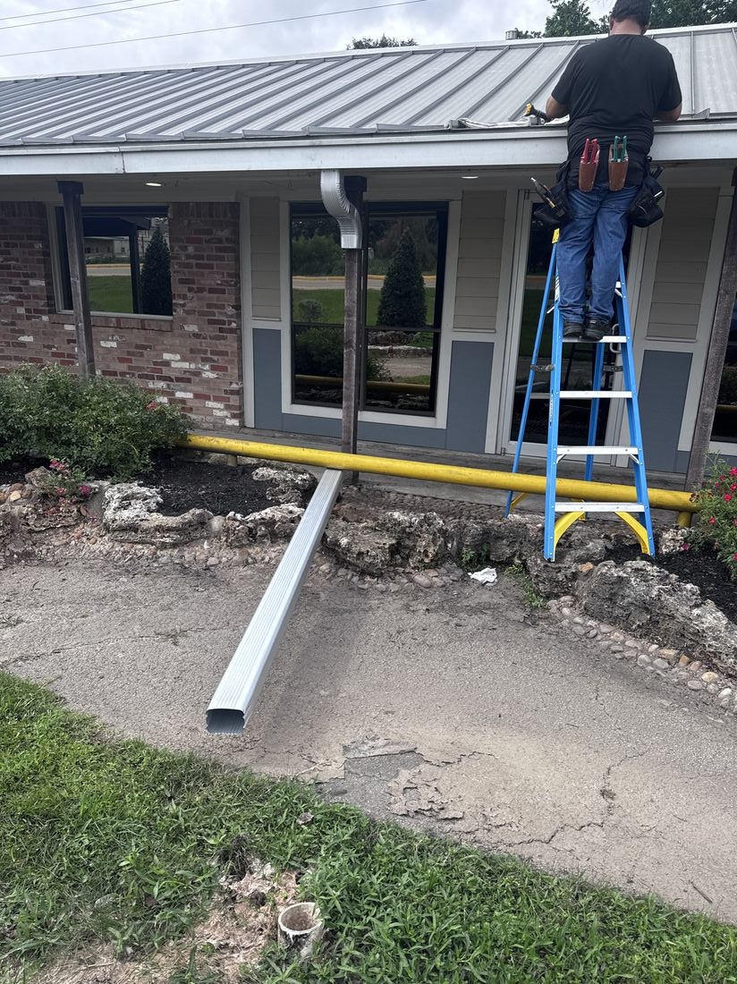 Installer on ladder mid gutter and downspout installation in Conroe, TX